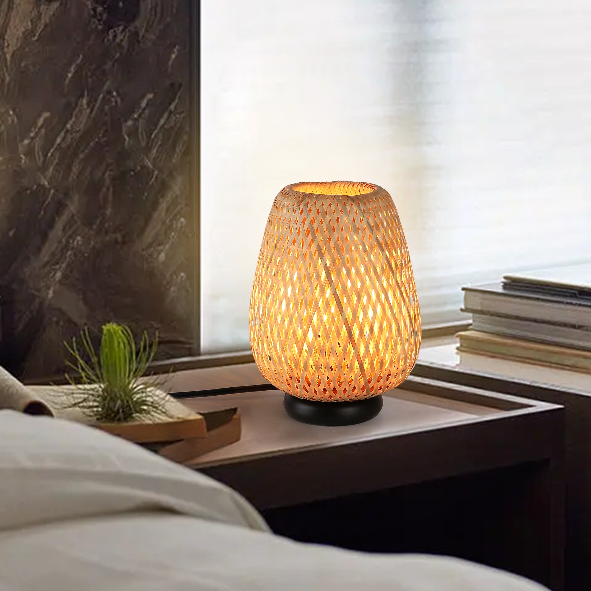 Woven rattan table lamp with natural basket shade and black base on a bedroom or living room side table
