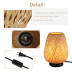 Woven rattan table lamp with natural basket shade and black base on a bedroom or living room side table