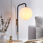 Opal globe plug-in wall sconce with matte black arm and brass accents