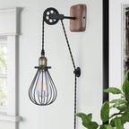 Industrial pulley plug-in wall sconce with natural wood backplate and black wire cage shade